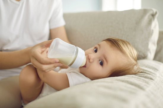 Baby trinkt aus einer Trinkflasche gefüllt mit Babymilch.