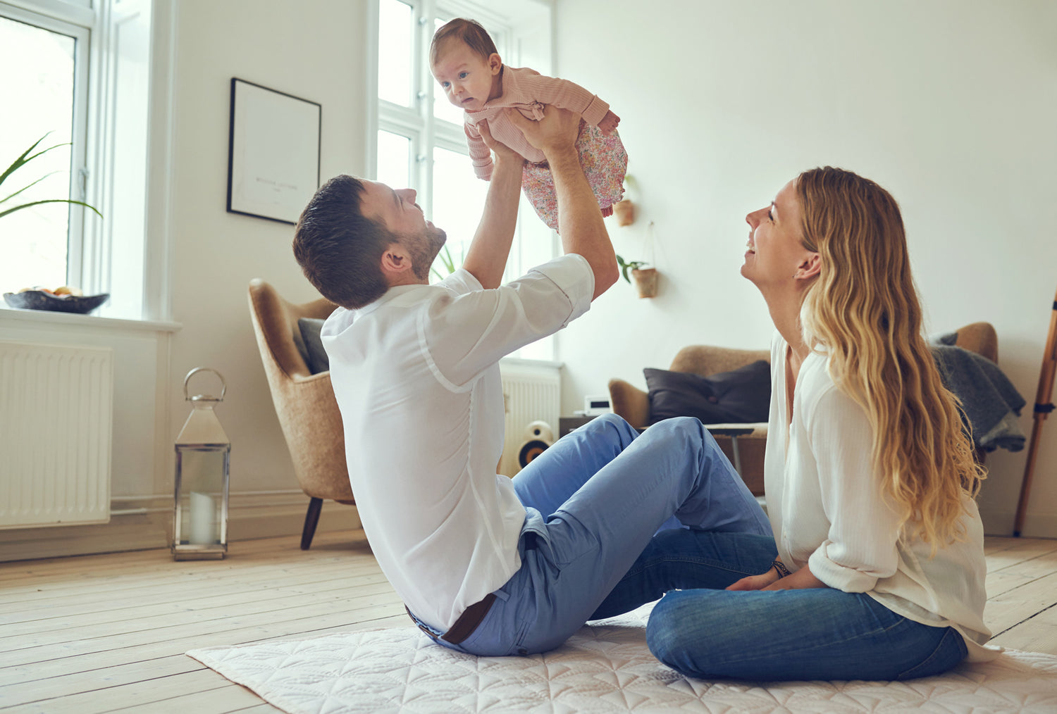 Junge Eltern spielen mit Baby im Wohnzimmer