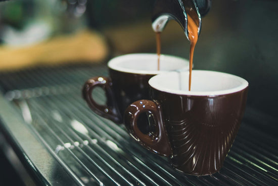 Zwei Espresso-Tassen werden gerade mit Kaffee befüllt.