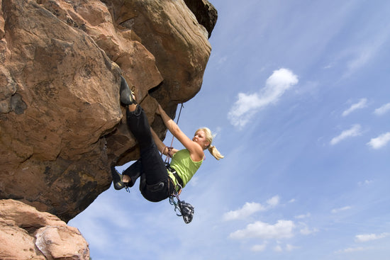 Eine Frau klettert einen Felsen hoch.