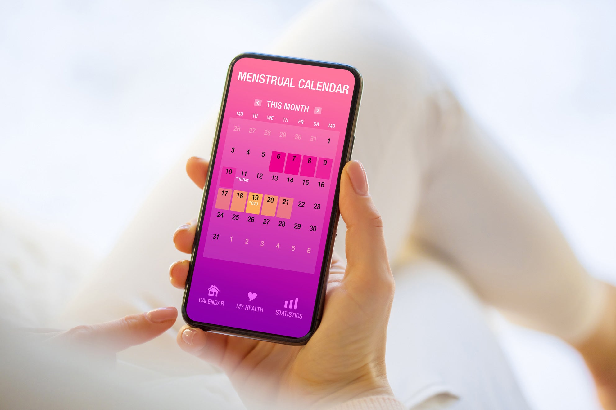 Frau hält ein Handy mit einem Menstruationskalender in der Hand.