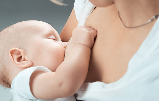 Schläfriges Baby wird gestillt